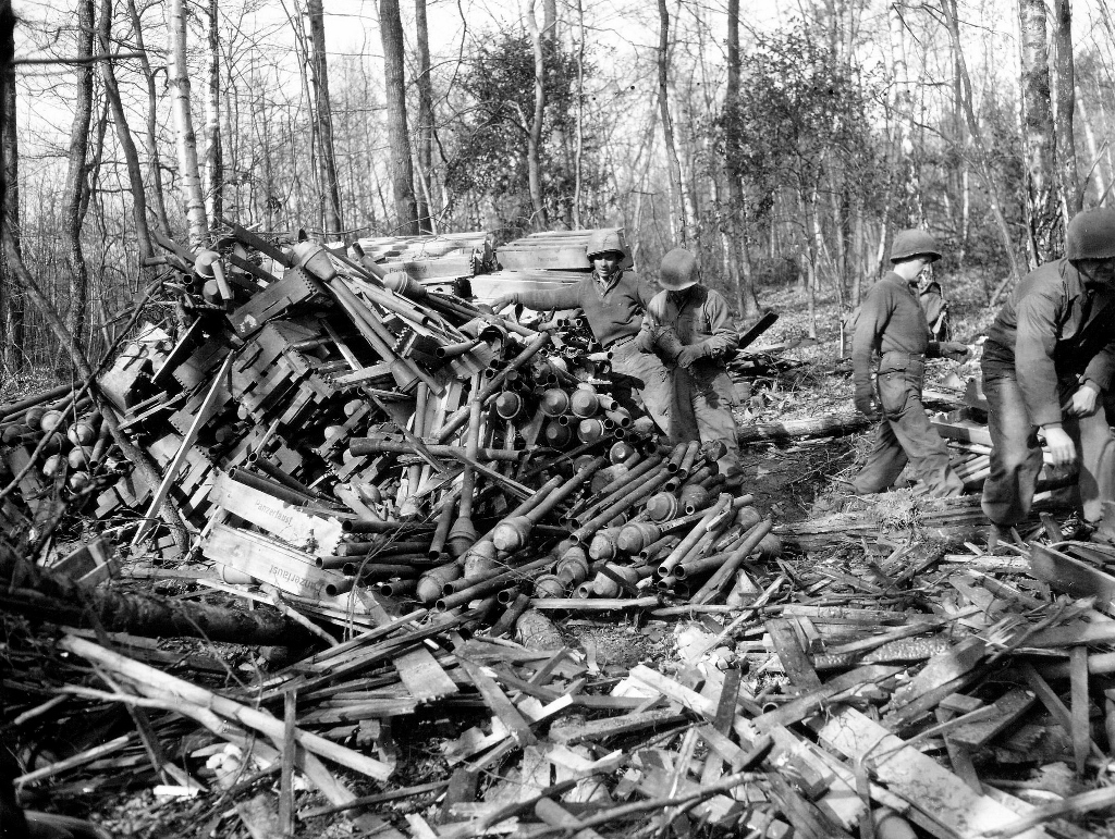 1945-Amerikanische Soldaten inspizieren einen im Wald zurückgelassenen Panzerfaust-Berg. Foto: ww2gallery, Bild / CC BY-NC Quelle: flickr
